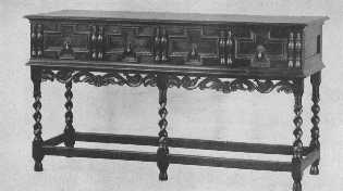 This Jacobean buffet is finely reproduced with the
exception of the spiral carving of the legs, which is too sharp and
thin, and gives the appearance of inadequate support. The split spindle
ornament was much used on furniture of the period.